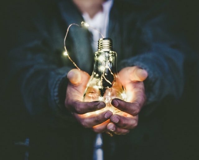 A man holding a lit up lightbulb for energy arbitrage application